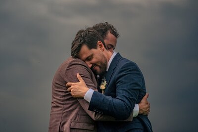 Un marié enlace son époux sous un ciel nuageux durant leur mariage en Allier.