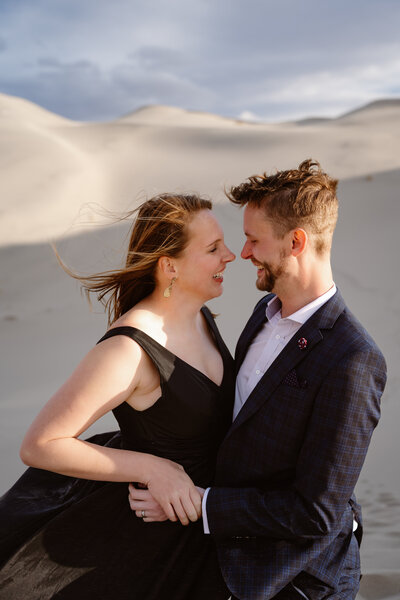 A newlywed couple with their arms around each other smiling