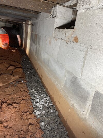 Interior crawlspace waterproofing in progress by APS Waterproofing, showing drainage preparation to protect against water intrusion.