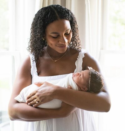 mother looking down at her newborn baby in her arms sleeping
