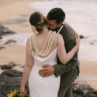 Bride and groom embracing before their ceremony, with the bride wearing a low back dress