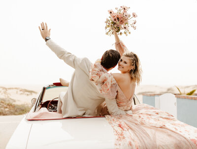 Bride and groom excited on back of vintage car at Southern California wedding