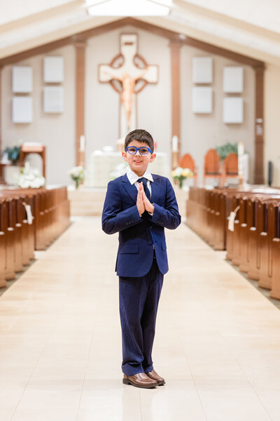 Young boy in a suit posed for portrait in a church.