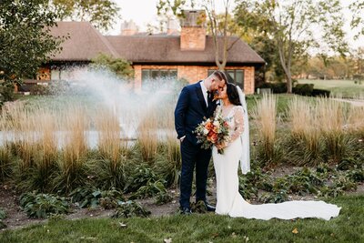 The bride to be sits between her fiancé's legs while he wraps his arms around her and they share a loving glance