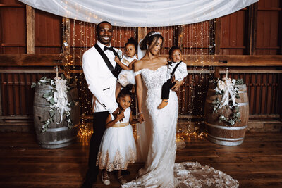 A bride and groom pose with their three children for their wedding portraits