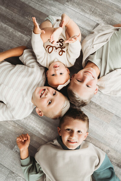 A family of 3 embraces and snuggles together in the Bismarck Studio of Nikii Pix Photography during their milestone session on their baby's first year collection.
