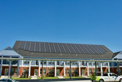 Large rooftop solar array on a multi-unit residential building under a clear blue sky