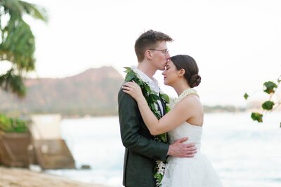 A person kissing their partner's forehead as they have their arms around each other 
