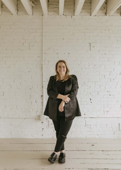 Renee in black outfit and white brick background