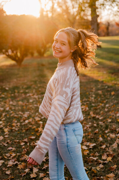 A high school senior girl twirls for the camera.