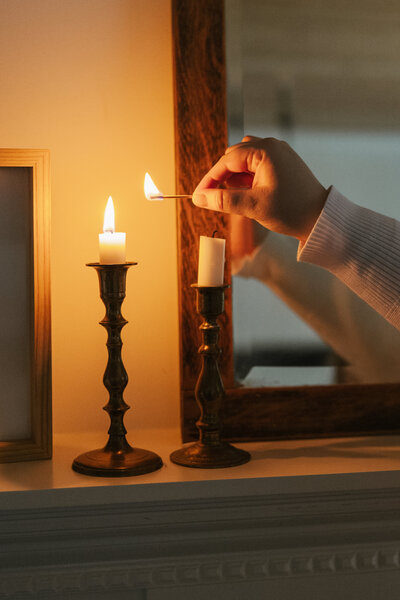Hand lighting candles on candlesticks with a match