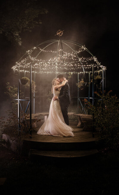 Photo de couple de nuit sous un kiosque éclairé aux Pavotube au Château de Sainte-Offenge, en Haute-Savoie – une ambiance cinématographique et créative pour un mariage hors du commun