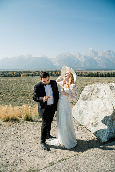 bride and groom drinking champagne in front of mountains
