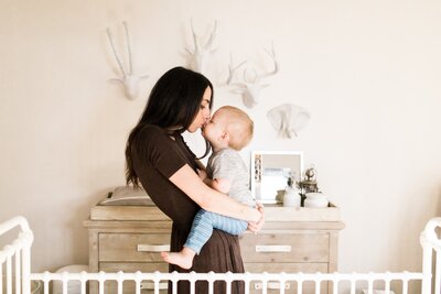 Mother holding her toddler in a nursery room for a Pittsburgh family photography session.