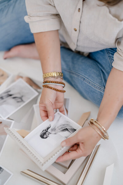 Close-up of a client selecting prints for a custom photo album with Suzanne Karp from Little Palm Photography, showcasing natural tones and timeless design.