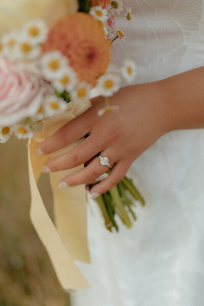 Close up portrait of a bride holding her bridal bouquet. The main focus of photo is her wedding ring on her finger.