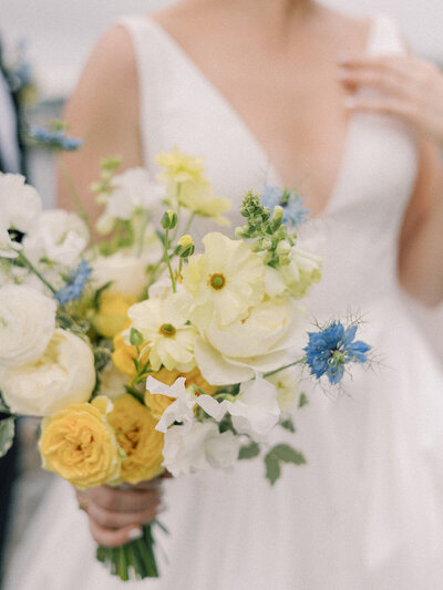 Bride folding flowers that are soft yellow, white and a pop of blue.