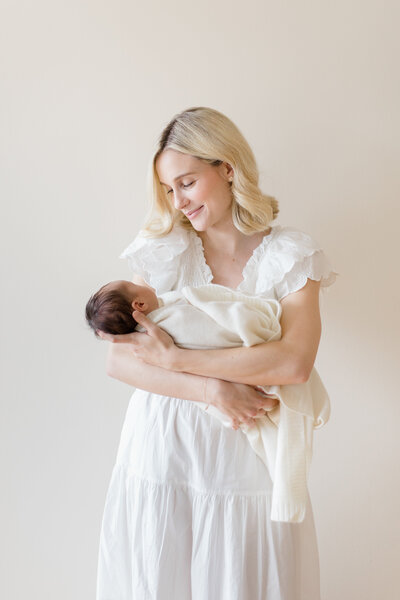 Mom holding newborn baby in studio by NYC family photographer