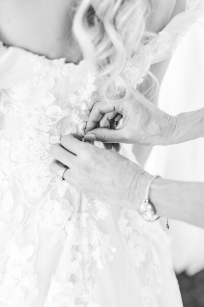 Wedding Photographer Atlanta Georgia | Black and white photo closeup of a Mother of the Bride buttoning the Bride's Lace Wedding Dress 
