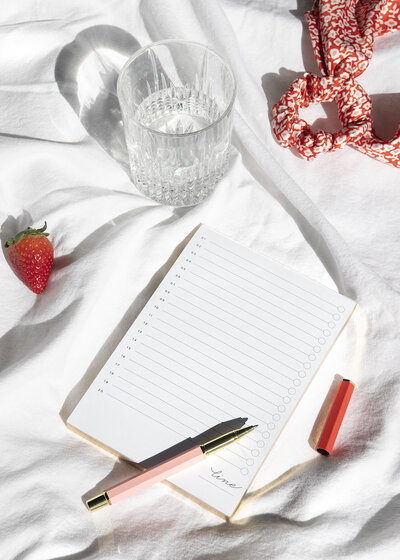 Notebook with pen, strawberry, scrunchie, and water glass