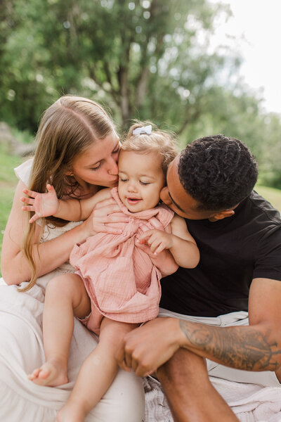 Mother kissing toddler while father holds them