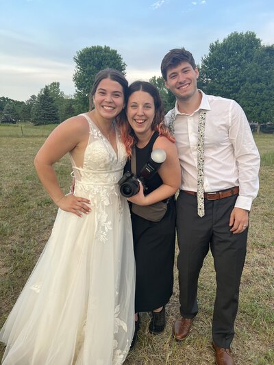 Abi Teeters of Abi Jane Photography posing with wedding couple