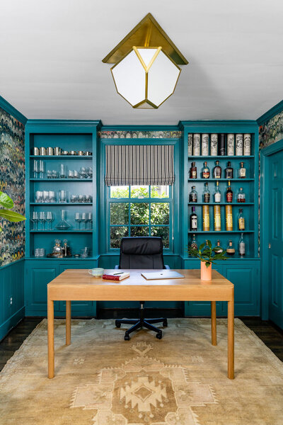Bold home office space with teal blue built in bookcases and brown desk