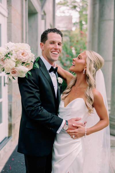 A newlywed couple smiles, holding one another, at an Ellis Preserve wedding.