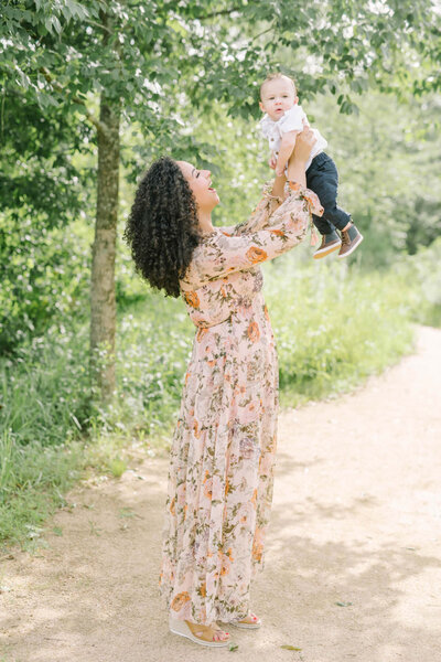 Mother lifts her young toddler and smiles