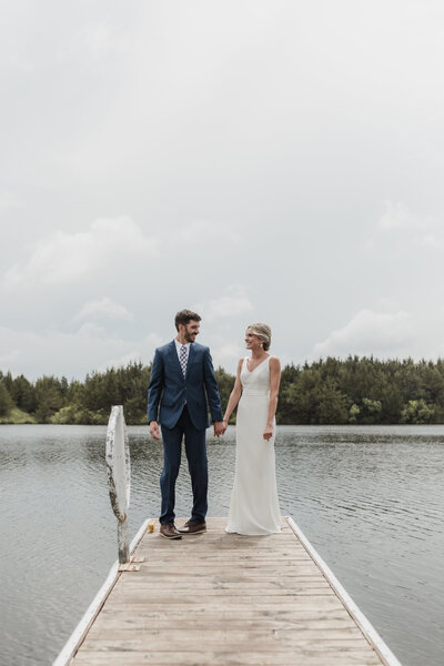 bride and groom stand on dock