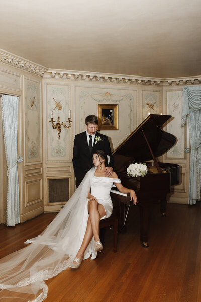 Picture of bride and groom sitting on a piano in a montana chateau