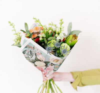 A tied bag of salted caramel popcorn with pretzels and praline pecans