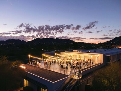 Outdoor rooftop reception at Mountain Shadows wedding venue in Scottsdale, with string lights glowing over guests at sunset, captured by Mountain Shadows wedding photographers.