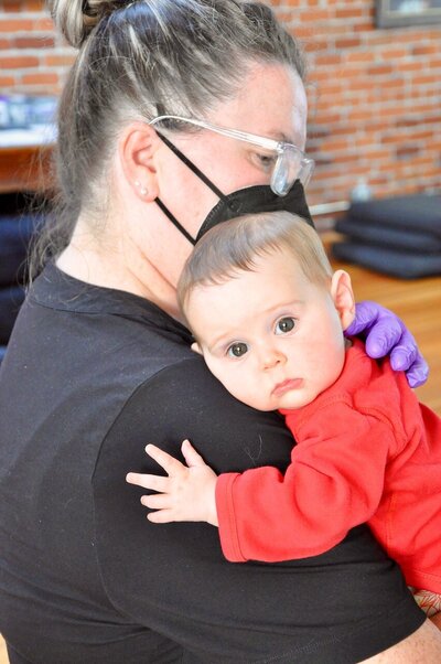 Woman holds a baby during an infant craniosacral therapy session.