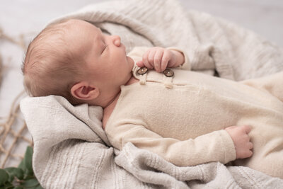 Side view of newborn boy in white pajamas at studio newborn session in Burlington, Connecticut