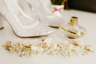 sparkly high heels with floral headband and perfume bottle lying next to it