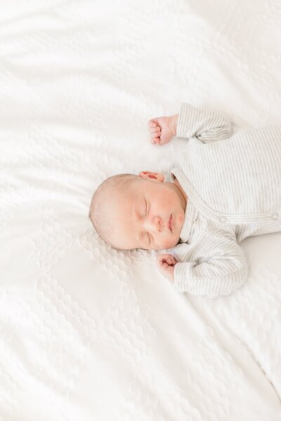 baby sleeps on bed during in home newborn photo session with Sara Sniderman Photography in Natick Massachusetts