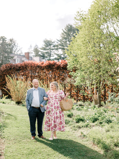 Husband and wife walk along a grassy path arm in arm while laughing