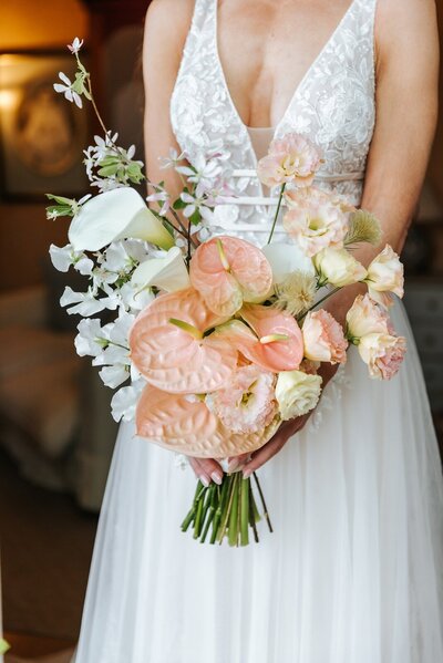 Bride in a white wedding dress holding a bouquet of light peach flowers