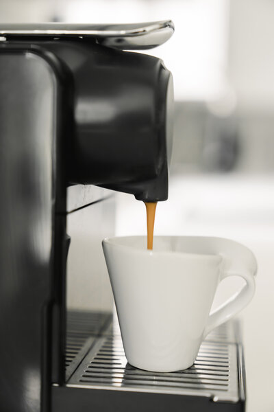 Espresso pouring from a sleek coffee machine into a white mug, representing efficiency and simplicity, mirroring the streamlined systems offered by The Systems Café