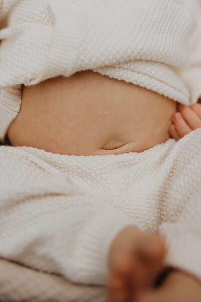 Newborn baby's tummy peeks out from knitwear set