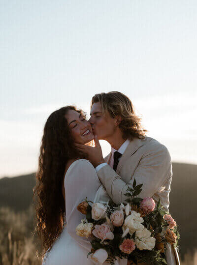 Groom Kissing Bride with Floral Bouquet