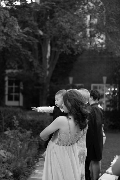 Baby being held by sister and reaching out toward parents
