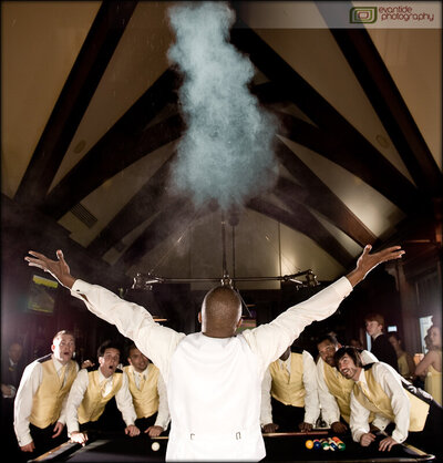 Groom blowing out cigar smoke in vaulted room