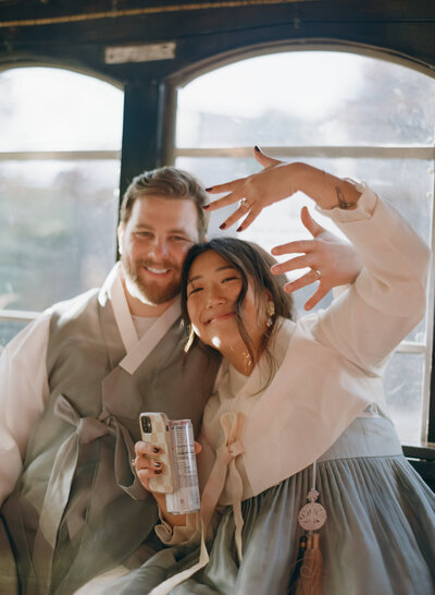 Two brides holding hands, laughing while standing in a park