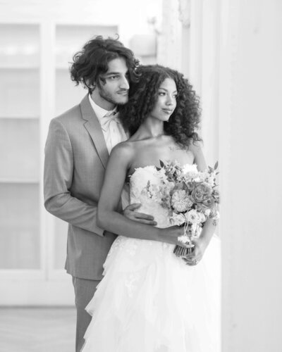 bride and groom looking out a window of the DAR while holding each other close