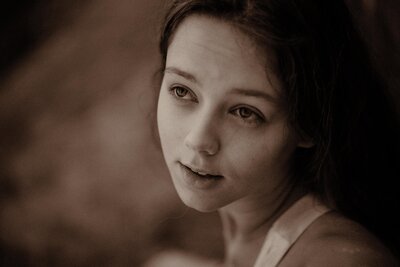 Models face looking up with a rock background. The portrait is sepia and soft.