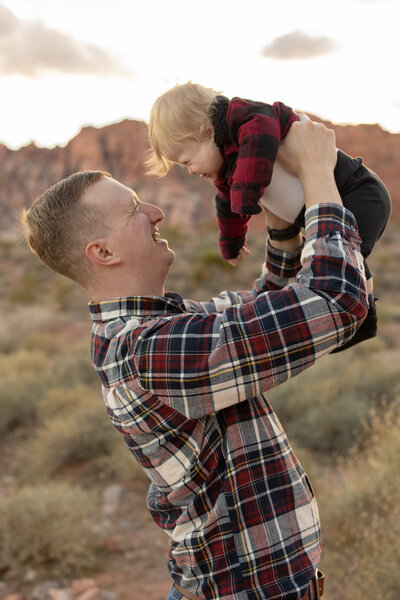 dad holding toddler in the air during their portrait session with alexis dean photography near Las Vegas