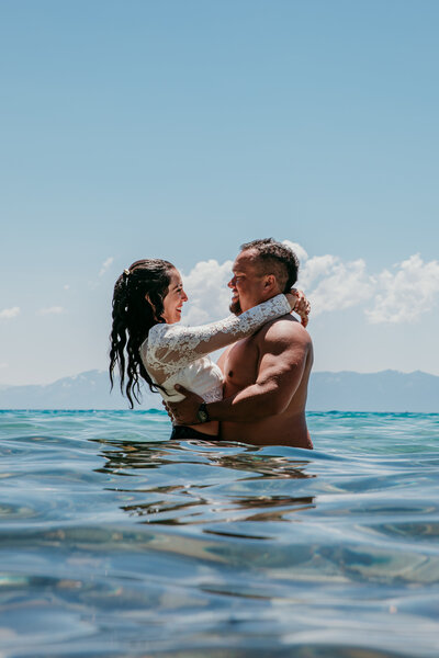Groom feeding bride a bite of chocolate cake during an intimate elopement celebration at Sand Harbor in Lake Tahoe, surrounded by boulders and natural decor with joyful expressions.