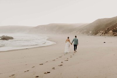 bride and groom walking down the beach